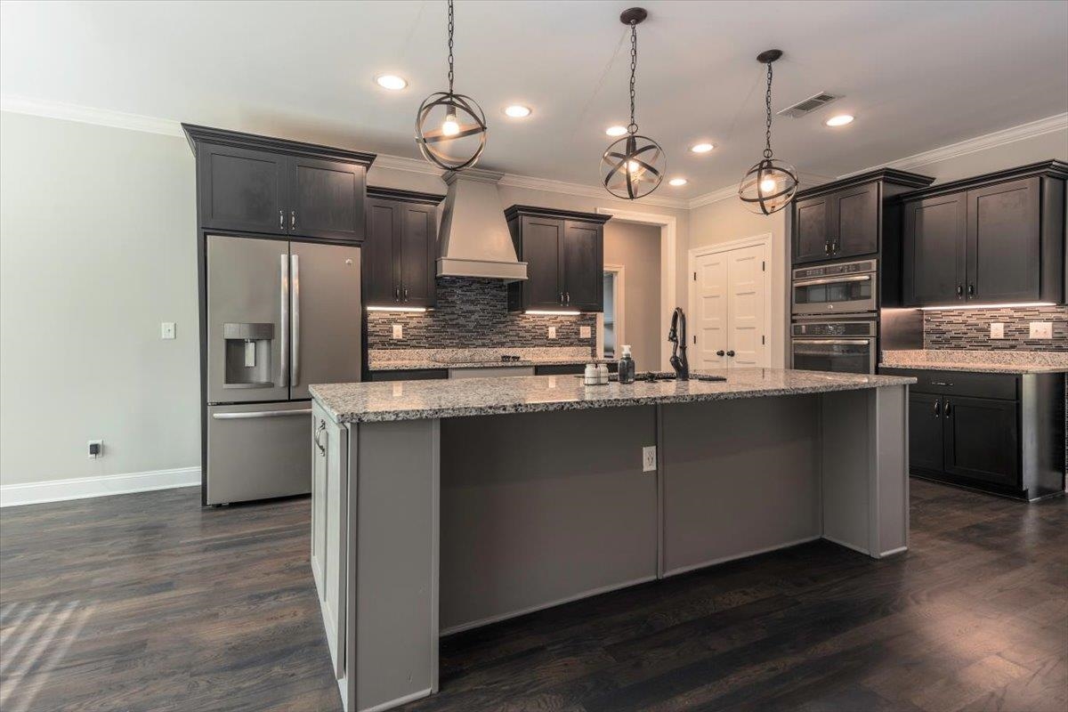 3328 Straw Bridge Road Olive Branch, MS 38654 - Photo 12 of 28 Kitchen featuring dark wood-finish flooring, a central island with granite countertops, dark cabinetry, and integrated stainless steel appliances