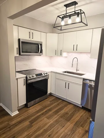 a kitchen with stainless steel appliances white cabinets a sink and a stove