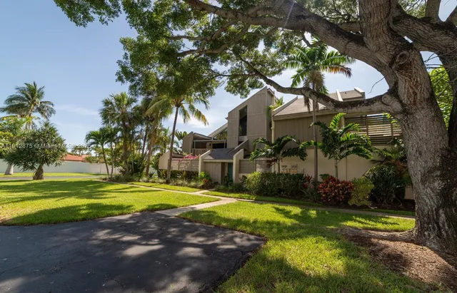 a view of a swimming pool with a yard and palm trees