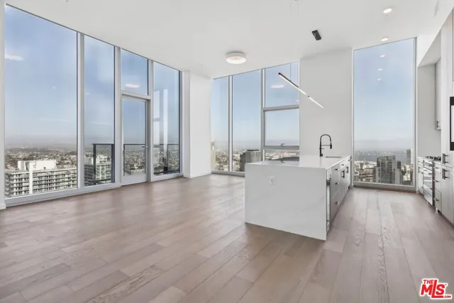 a view of a kitchen with kitchen island a sink wooden floor and living room