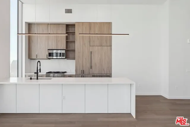 a kitchen with kitchen island a counter top space wooden floor and appliances