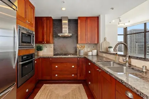 a kitchen with stainless steel appliances granite countertop wooden cabinets a sink dishwasher a refrigerator and a stove