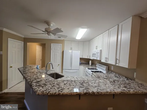 a view of granite countertop kitchen with wooden floor and stainless steel appliances