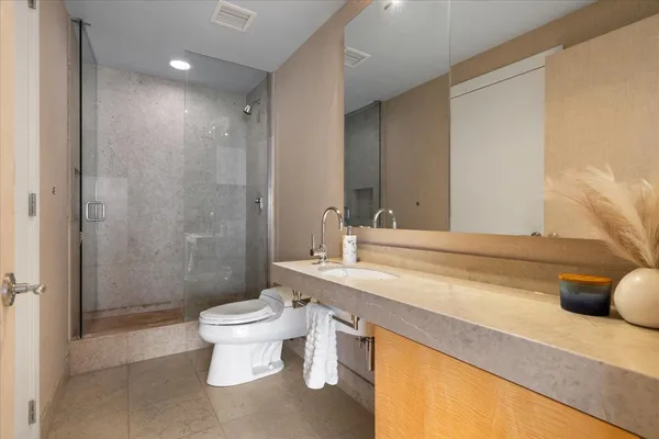 a bathroom with a granite countertop sink a toilet a mirror and shower