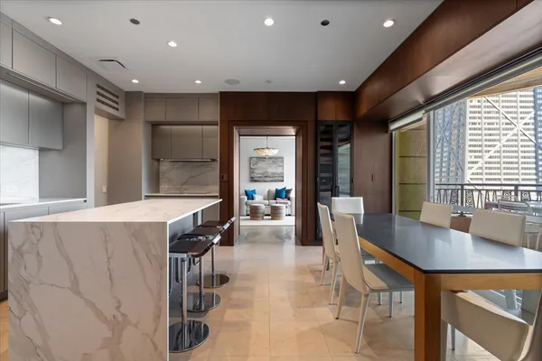 a dining hall with stainless steel appliances a dining table and chairs with kitchen island