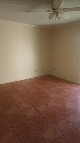 a view of an empty room and chandelier fan