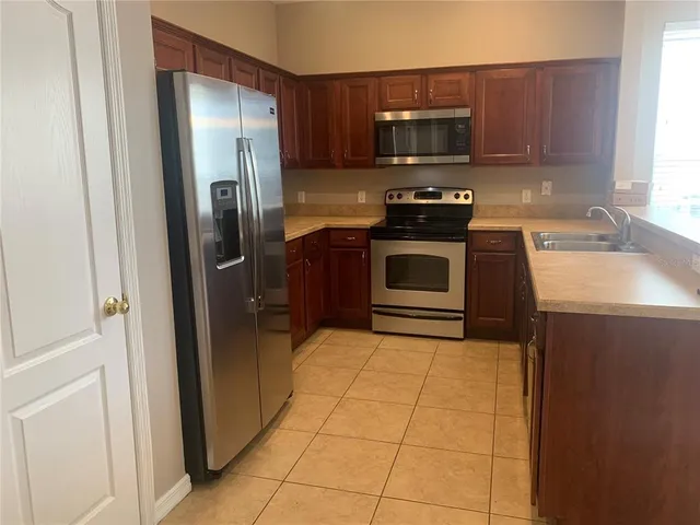 a kitchen with granite countertop a refrigerator and a stove top oven
