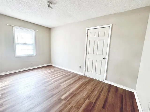 an empty room with wooden floor and a window