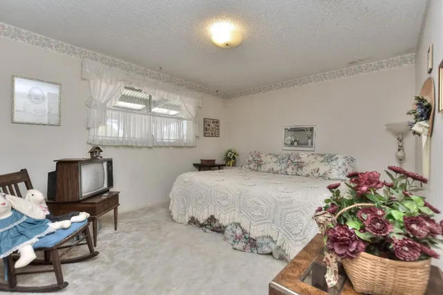 a bedroom with a bed potted plant on dresser and a window