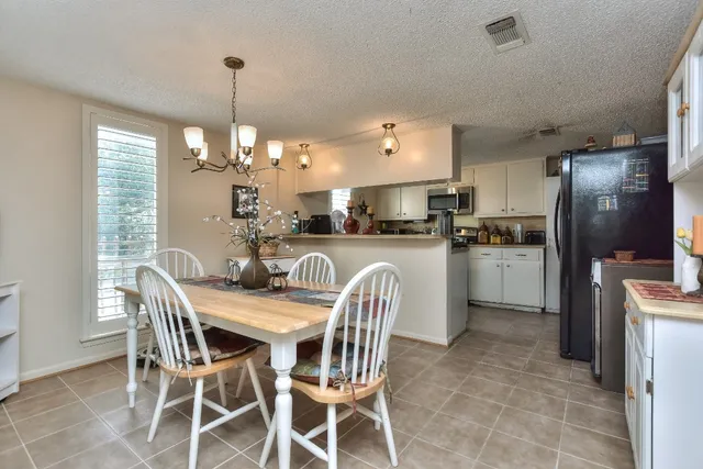 a kitchen with stainless steel appliances kitchen island granite countertop a refrigerator a stove a sink dishwasher a dining table and chairs