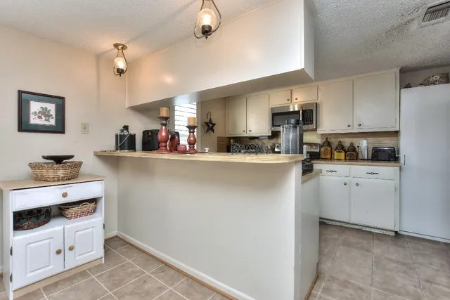 a kitchen with stainless steel appliances a refrigerator sink stove and white cabinets