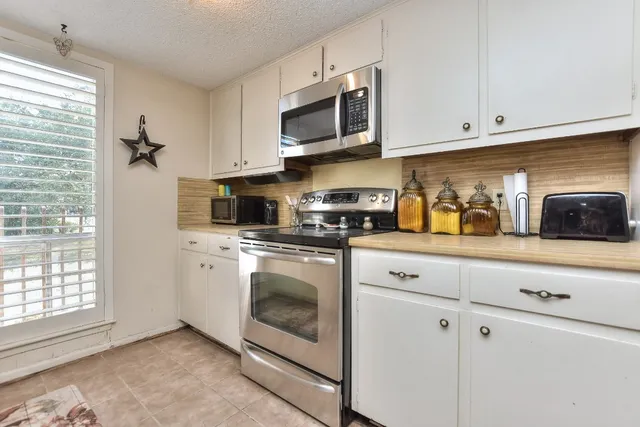 a kitchen with stainless steel appliances granite countertop white cabinets a sink and a window