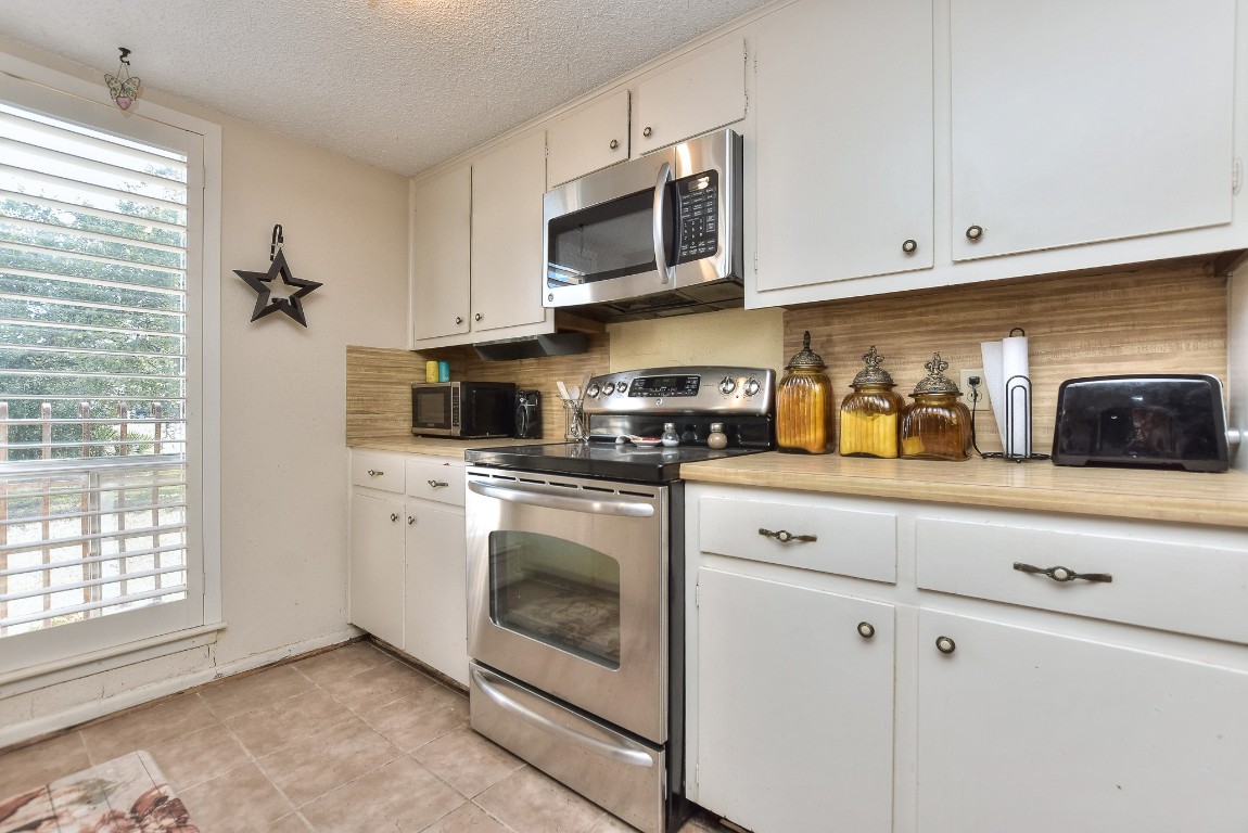 118 Oak Ridge Circle Georgetown, TX 78628 - Photo 10 of 40 a kitchen with stainless steel appliances granite countertop white cabinets a sink and a window
