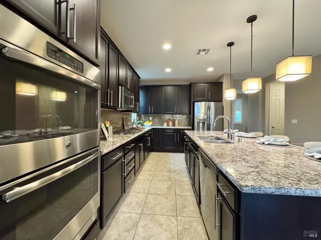 a kitchen with stainless steel appliances granite countertop a sink stove and cabinets