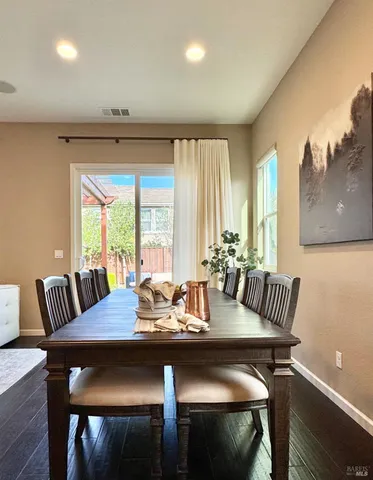 a dining hall with couches a dining table and chairs with wooden floor