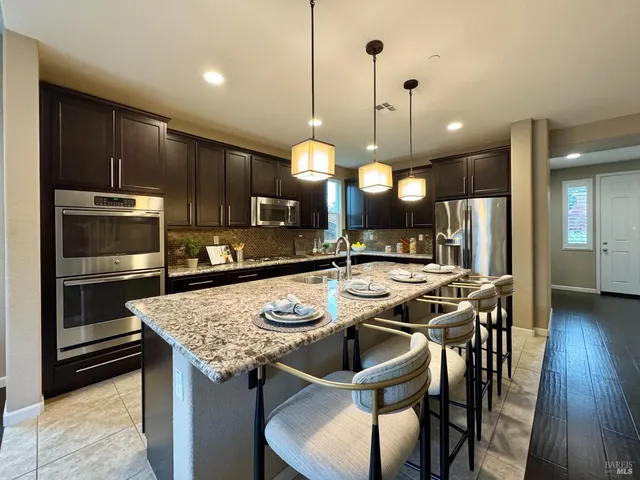 a kitchen with stainless steel appliances granite countertop a sink a stove and a wooden cabinets