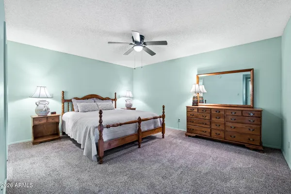 a spacious bedroom with a bed a couch and a chandelier