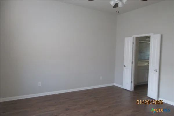 a view of an empty room with wooden floor & closet