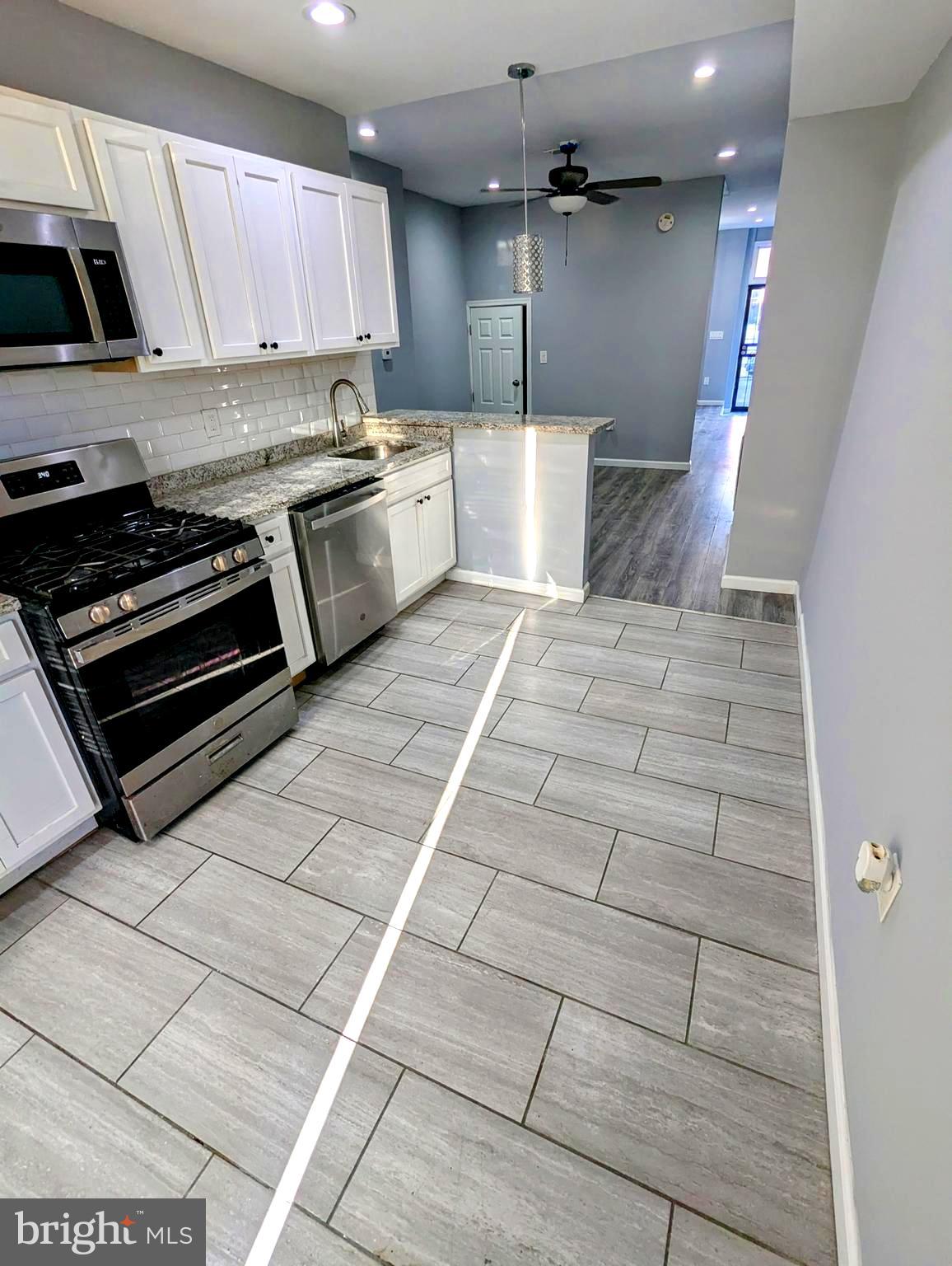 626 North Payson Street Baltimore, MD 21217 - Photo 7 of 23 a kitchen with stainless steel appliances granite countertop a stove a sink and a microwave