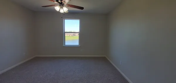 an empty room with a window and a fan