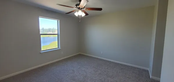 an empty room with a window and a fan