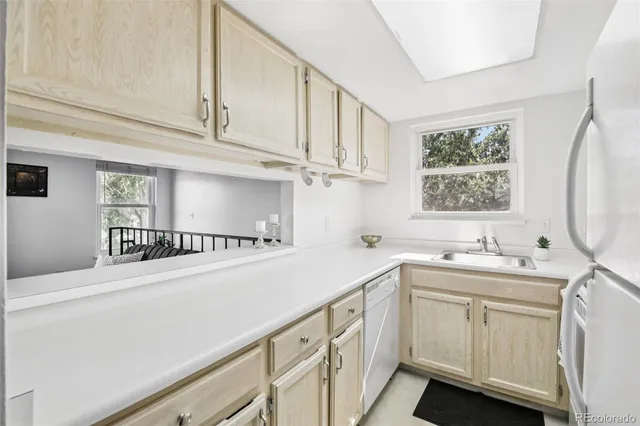 a kitchen with white cabinets a sink a window and appliances