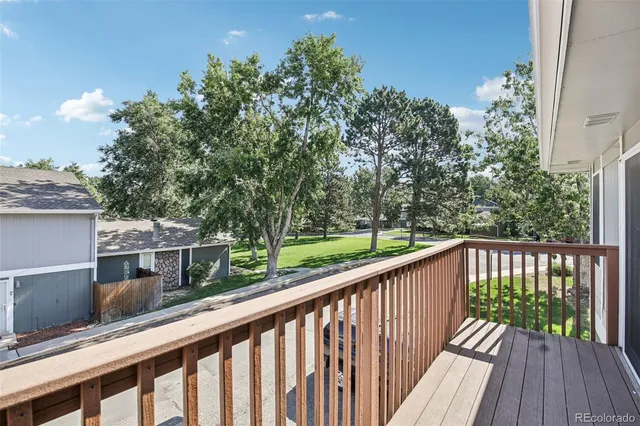 a balcony with wooden floor and trees in the back
