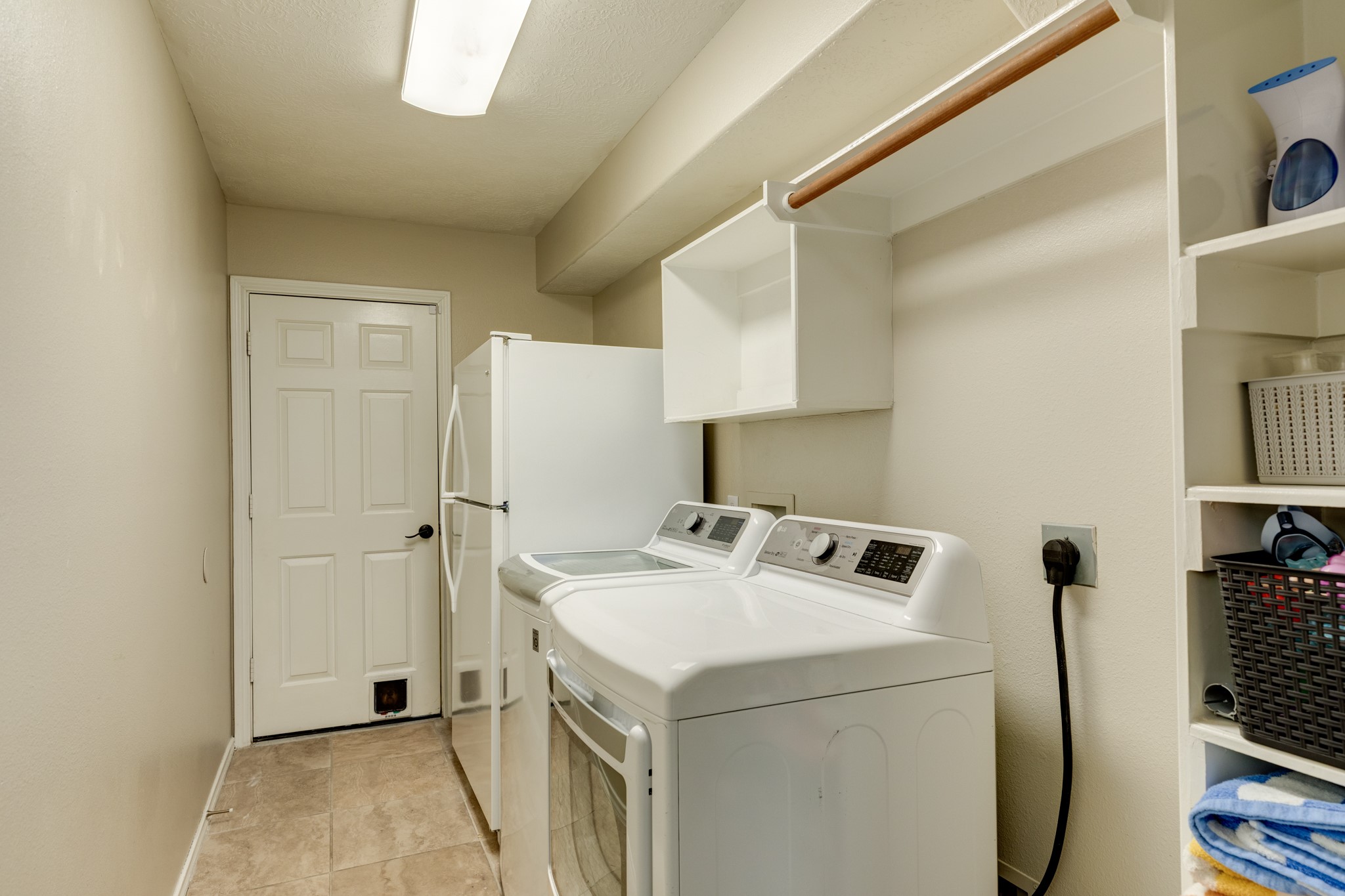 4113 Merlet Drive Pearland, TX 77584 - Photo 17 of 36 Laundry room features ample space, suitable for an additional refrigerator or freezer, along with storage solutions and a clothesline rack. The room also serves as the entrance to the two-car garage.