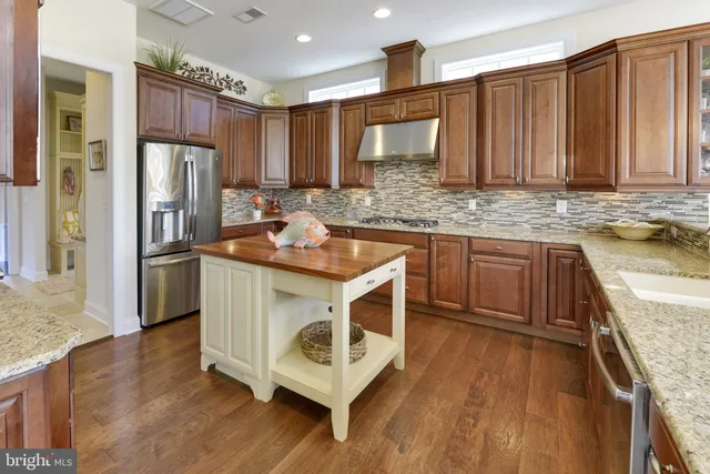 a kitchen with kitchen island granite countertop wooden cabinets stainless steel appliances a sink and a center island