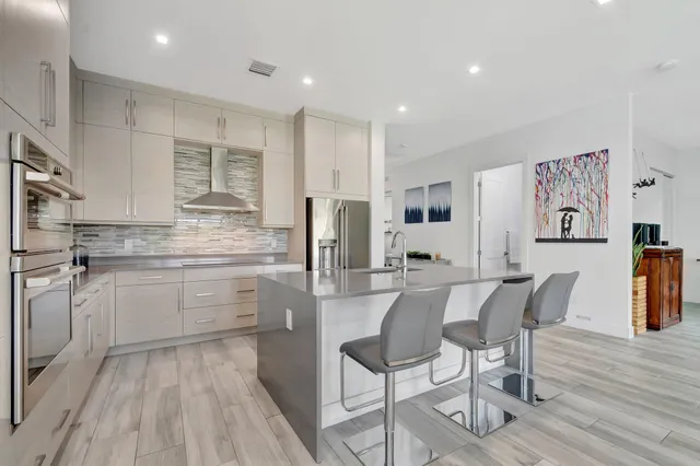 a kitchen with stainless steel appliances kitchen island granite countertop a refrigerator a stove a sink a dining table and chairs