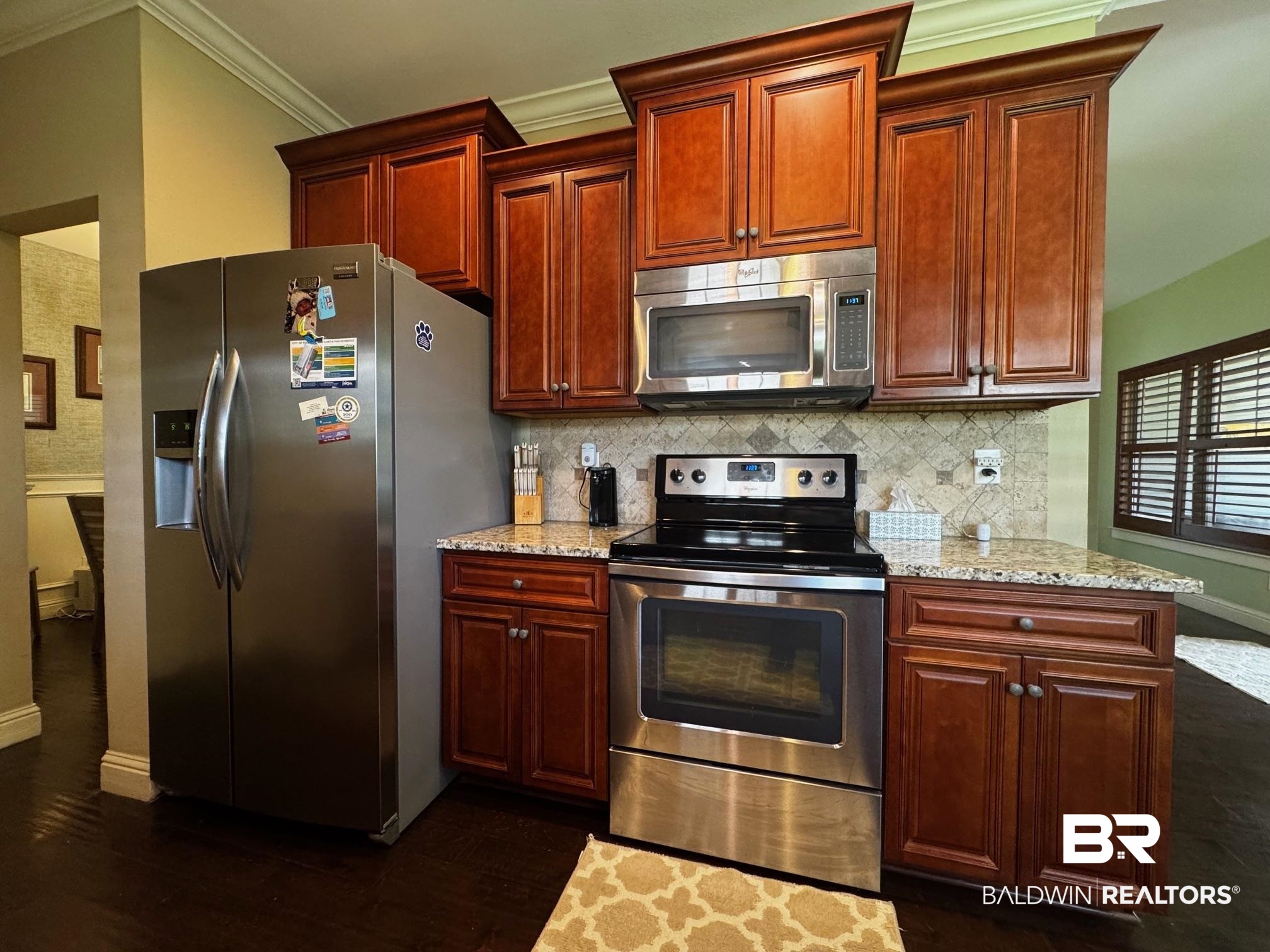 1030 Crown Walk Drive Foley, AL 36535 - Photo 9 of 40 Kitchen featuring light stone counters, decorative backsplash, appliances with stainless steel finishes, and ornamental molding