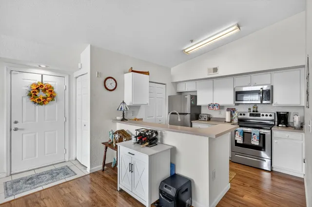 a kitchen with stainless steel appliances a stove a sink dishwasher and a refrigerator with wooden floor