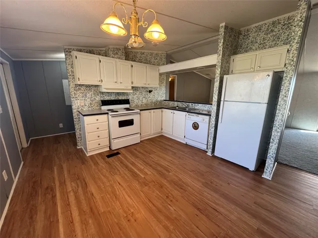 a kitchen with stainless steel appliances granite countertop a refrigerator a sink dishwasher a stove and white countertops with wooden floor