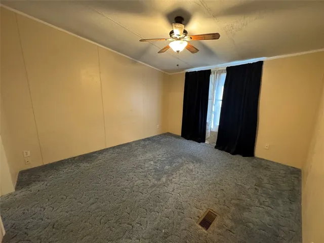 an empty room with a chandelier fan and windows