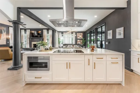 a large white kitchen with lots of counter space a sink appliances and cabinets