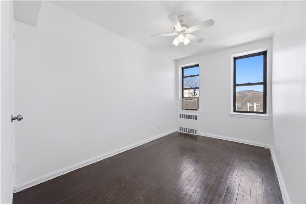 302 96th Street, Unit 3H Brooklyn, NY 11209 - Photo 10 of 14 an empty room with wooden floor chandelier fan and windows