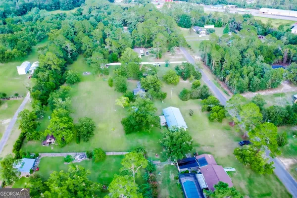 an aerial view of residential house with outdoor space and trees all around
