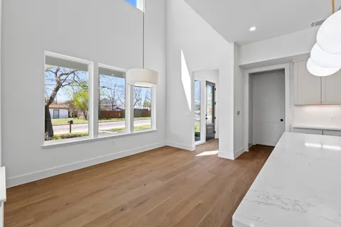 a view of a hallway with wooden floor and a bathroom