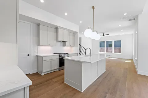 a kitchen with stainless steel appliances granite countertop a sink a stove and a wooden floors