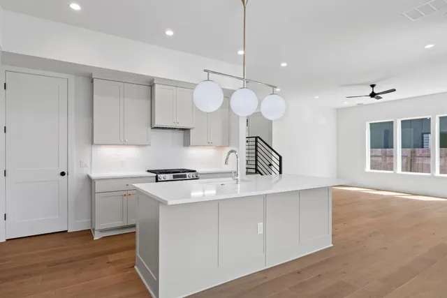 a large white kitchen with wooden floor and a sink