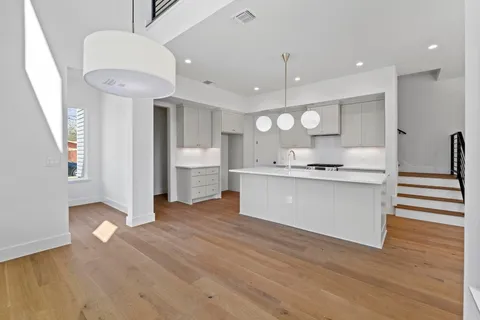 a large white kitchen with a sink a refrigerator and a stove top oven