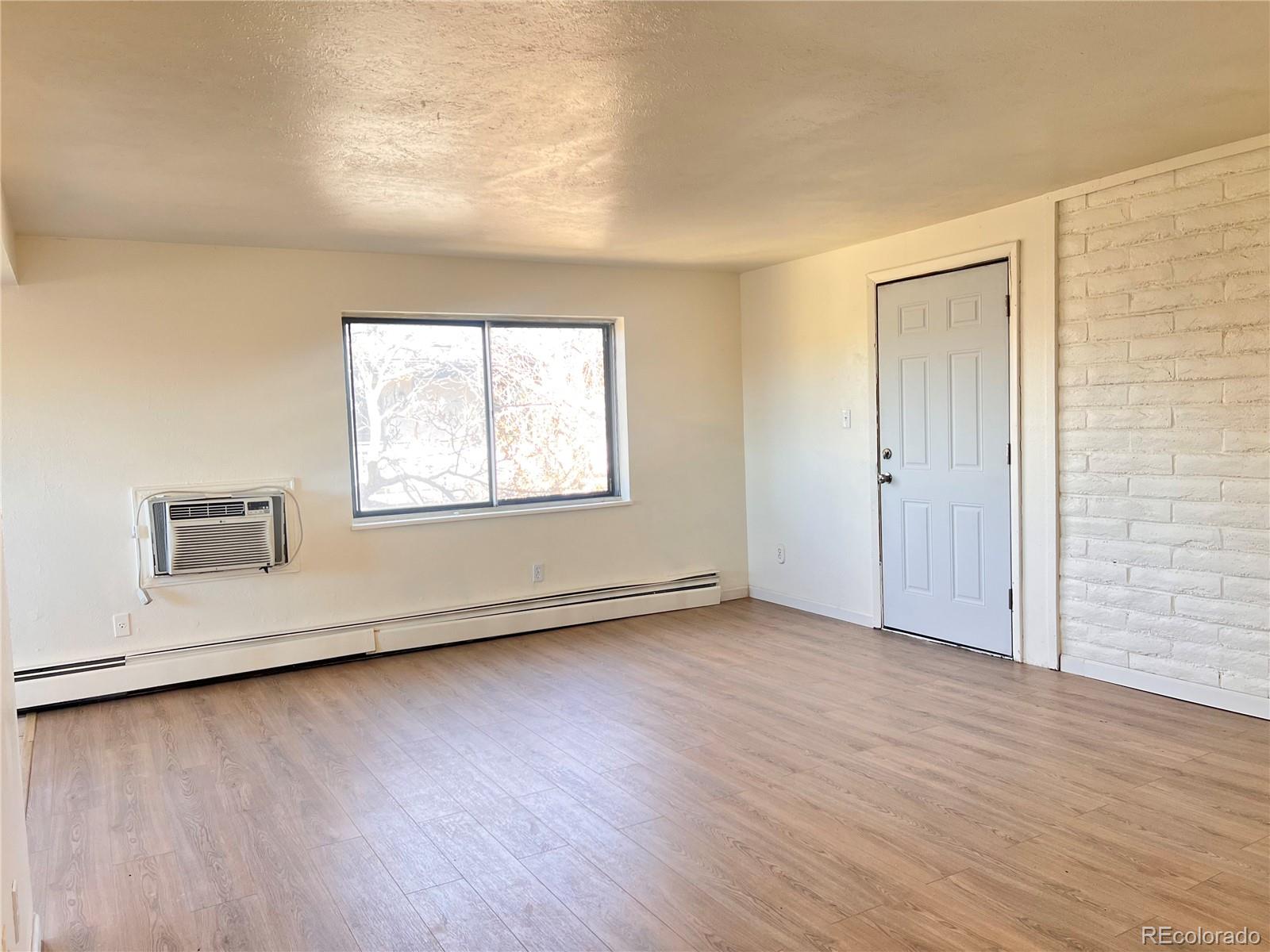 875 South Quebec Street, Unit 29 Denver, CO 80247 - Photo 2 of 13 an empty room with wooden floor and windows