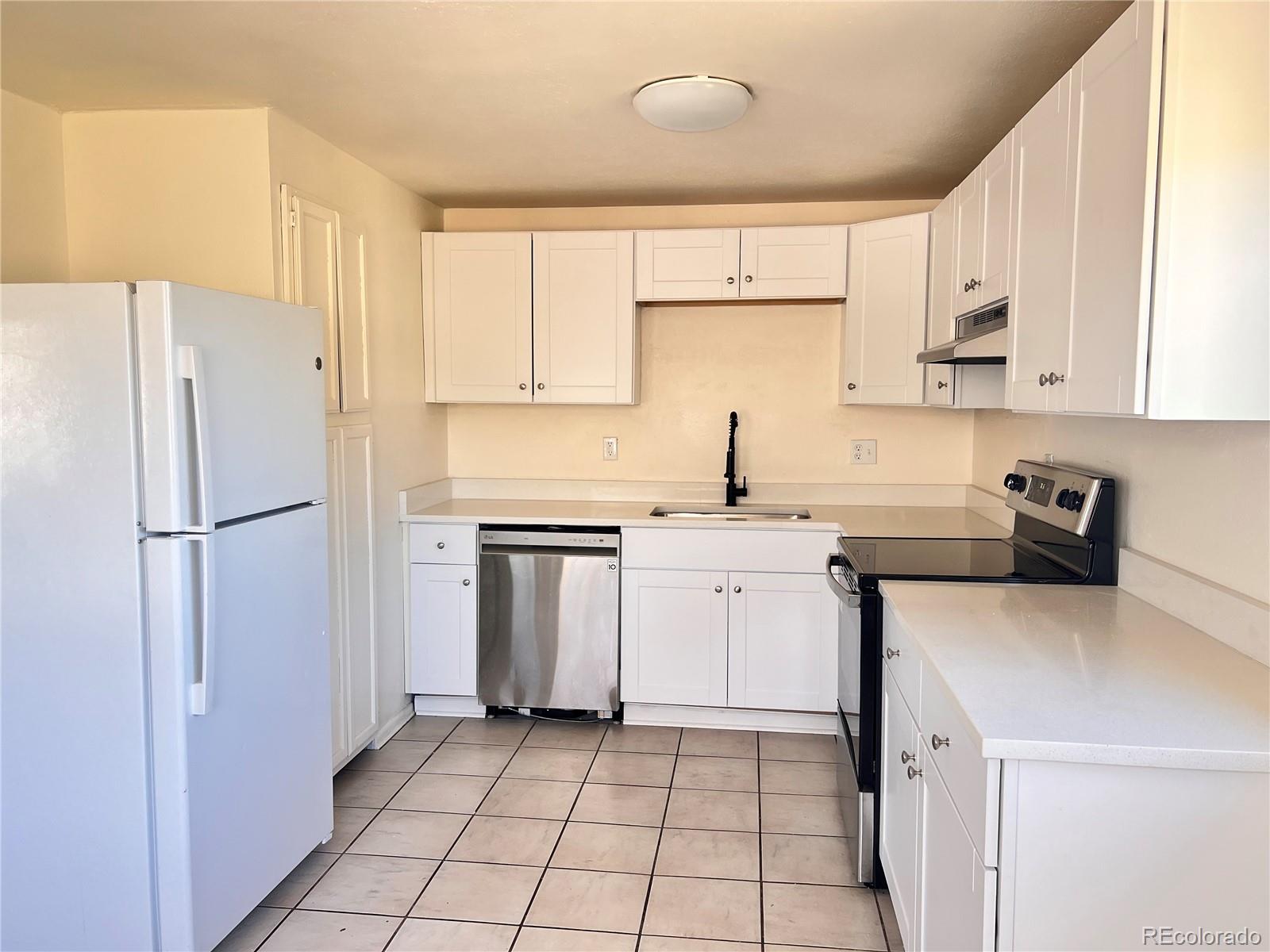 875 South Quebec Street, Unit 29 Denver, CO 80247 - Photo 4 of 13 a kitchen with a sink a refrigerator and white cabinets