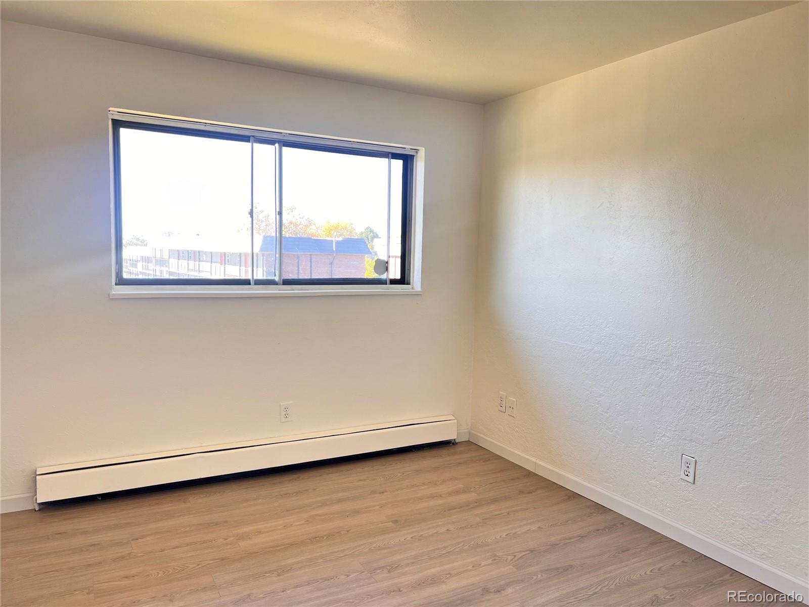 875 South Quebec Street, Unit 29 Denver, CO 80247 - Photo 8 of 13 an empty room with wooden floor and windows