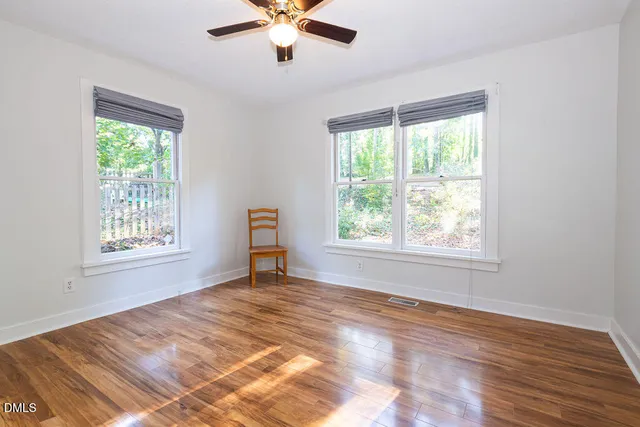 a view of an empty room with a window and wooden floor