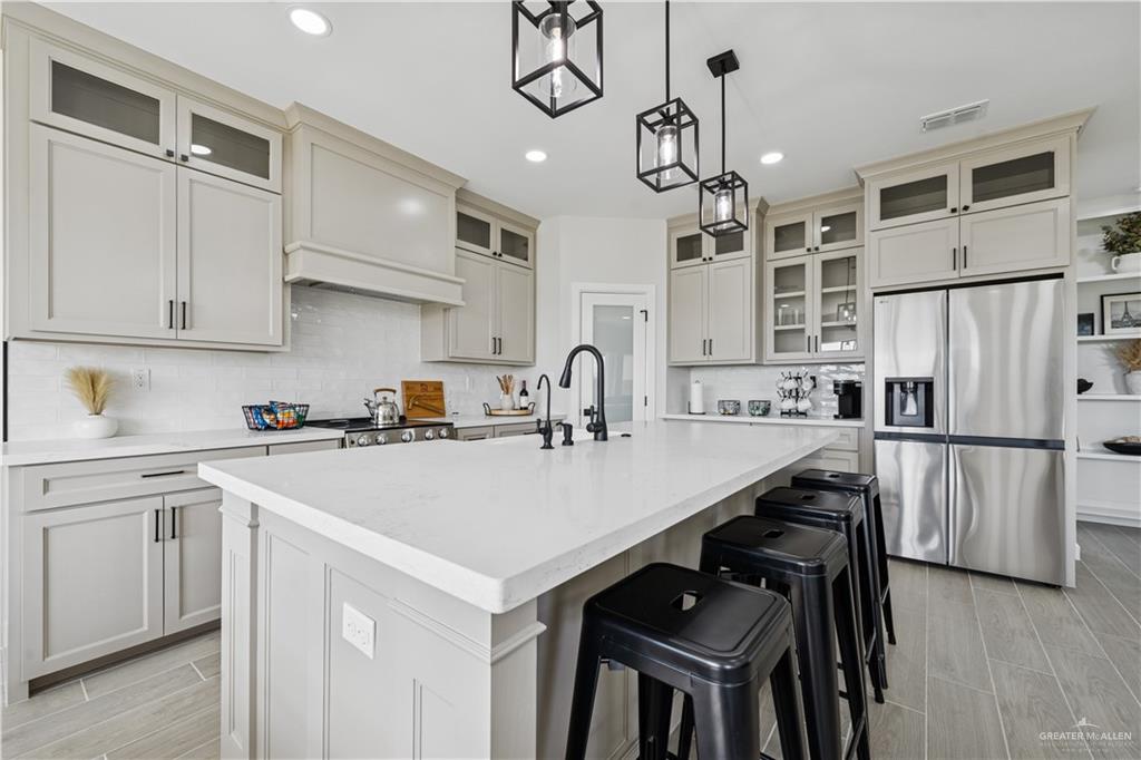 1013 Azalea Street Mission, TX 78573 - Photo 12 of 35 Kitchen with glass insert cabinets, stainless steel fridge, wood tiled floors, and recessed lighting