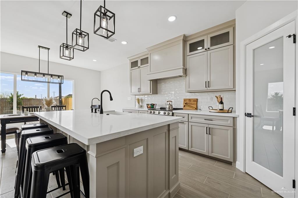 1013 Azalea Street Mission, TX 78573 - Photo 14 of 35 Kitchen featuring pendant lighting, plenty of natural light, backsplash, glass insert cabinets, and recessed lighting