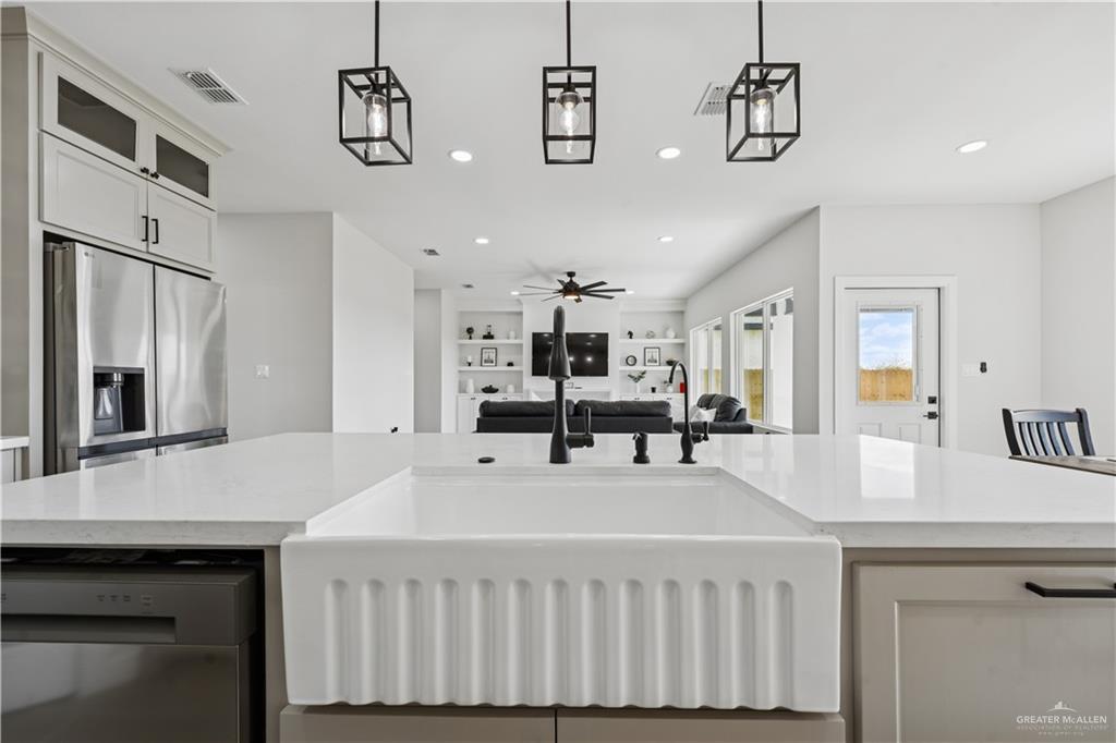 1013 Azalea Street Mission, TX 78573 - Photo 15 of 35 Kitchen with stainless steel appliances, white cabinets, decorative light fixtures, recessed lighting, and light stone countertops
