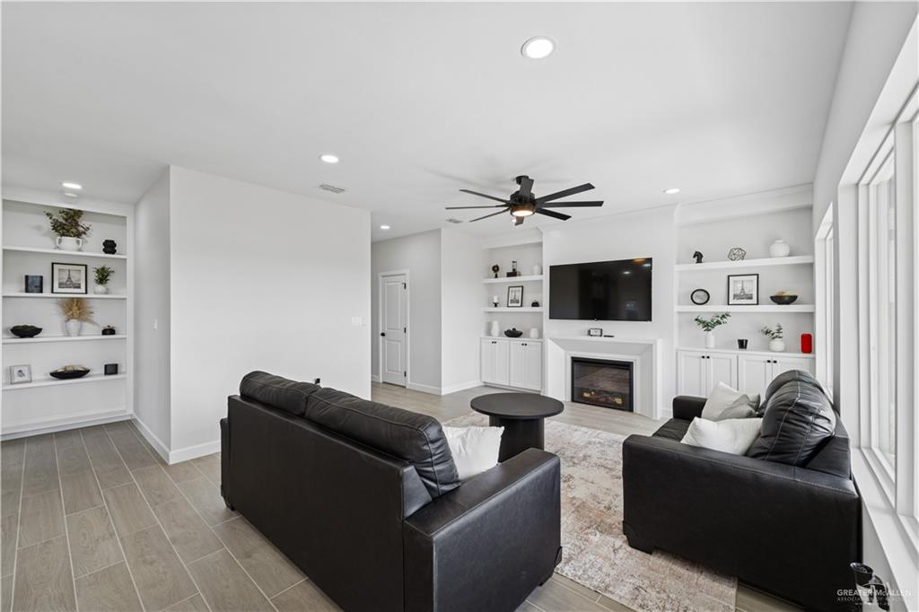 1013 Azalea Street Mission, TX 78573 - Photo 16 of 35 Living area featuring built in shelves, recessed lighting, light wood-style floors, a glass covered fireplace, and a ceiling fan