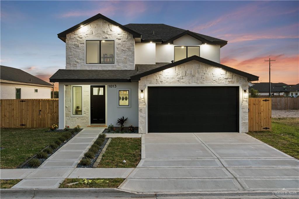 1013 Azalea Street Mission, TX 78573 - Photo 2 of 35 Contemporary home with stone siding, concrete driveway, a shingled roof, and a garage
